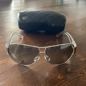 Authentic CHANEL ladies sunglasses. They are a silver frame with clear arms.